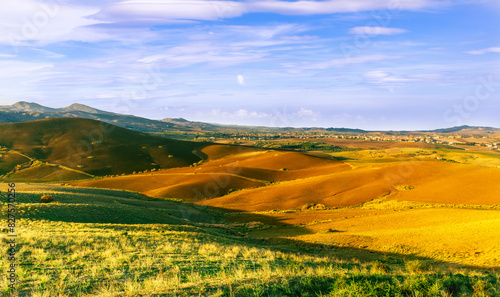 beautiful landscape in a yellow golden field in autumn or summer evening with nice rustic view of hills in countryside