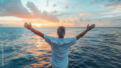 Man with arms wide open facing a beautiful ocean sunset, expressing freedom