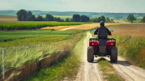 Rear back view of man wearing a helmet, driving ATV motocross quad bike on rural countryside field village road outdoors in the summer. Copy space, off-road terrain trail transport, mountain lifestyle