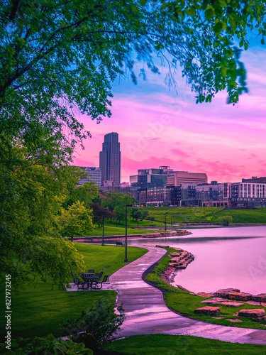 Omaha City Skyline at Sunrise over the Conagra Lake and vibrant green forest at the Heartland of America Park: The tranquil beauty of the midwestern metropolis in Nebraska