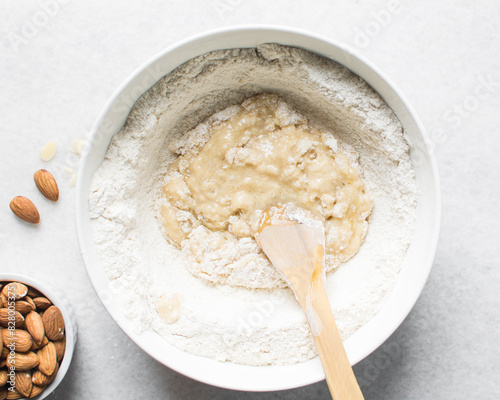 making almond biscotti dough in a white bowl, process of making almond cantucci cookie dough in ceramic mixing bowl