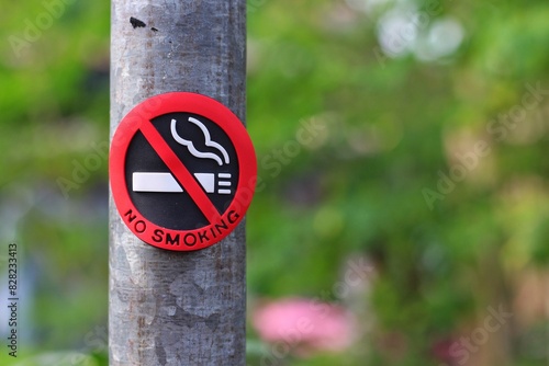 No Smoking sign on the pole in the public park with blur nature background