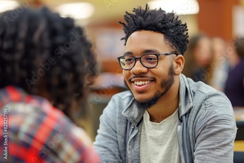 Smiling young man in glasses actively participating in a casual conversation in a group setting