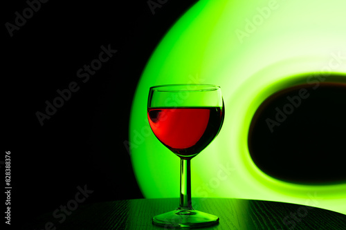 Kieliszek czerwonego wina na czarnym tle podświetlony zielona smuga światła 