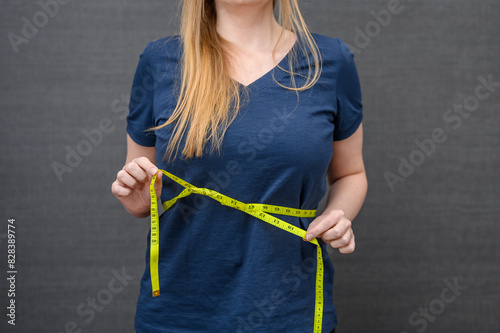 Kobieta mierzy obwód w pasie żółta miarka krawiecką 