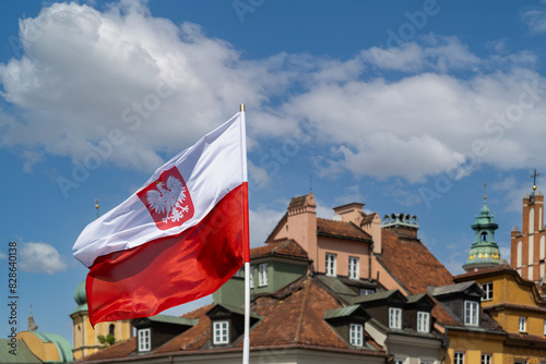 Polska flaga na tle dachów domów Strego Mista na Placu Zamkowym w Warszawie.