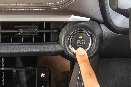 finger pressing the Engine start stop button of a car