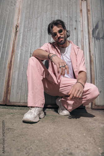 confident fashion man in pink clothes with sunglasses crouching