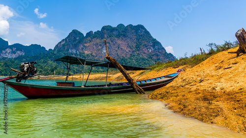 Wooden longtail boats on the shore of a lake surrounded by jungle (Khao Sok, Thailand)
