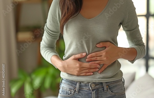 Woman experiencing excruciating pain in her stomach at home, woman experiencing stomach discomfort