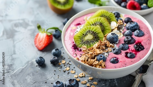 Pink berry smoothie bowl with granola kiwi blueberries light gray background