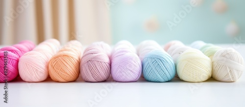 A white table with pastel colored cotton yarn balls for needlework providing a copy space image
