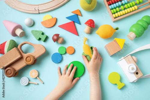 Toddler children activity for motor and sensory development. Baby hands with colorful wooden toys on table from above.