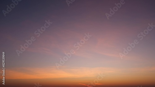 A serene sunrise with soft, warm hues of orange and yellow blending into a gentle gradient of light purple and blue as the sky ascends. The sky is mostly clear. Sunrise sky background. 