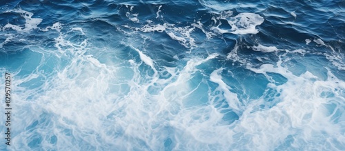 An impressive ocean background featuring a striking contrast between deep blue sea and foamy white waves when viewed from above with copy space image