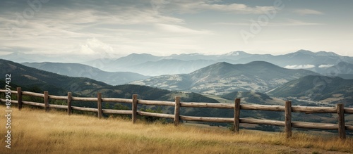 A fence along a mountain with cloudy skies in the background offering a serene view with copy space image