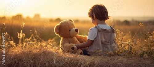 Child happily playing with a soft plush bear in the countryside on a sunny summer day against a copy space image