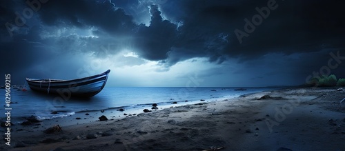 A boat rests on the tranquil seashore with a dramatic storm approaching in the background creating a sense of impending danger in the copy space image