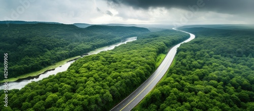 Aerial view of asphalt road lush forests and river in a stunning landscape photo taken by a drone on a summer day under a rainy sky with copy space image
