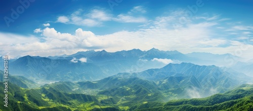 Lush green mountains set against a blue sky backdrop create a picturesque panorama in this stunning landscape with mountain peaks and valleys offering a breathtaking view with copy space image