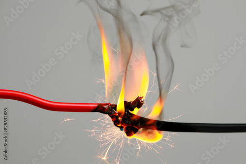 Electrical wire burning and sparking on light background, closeup