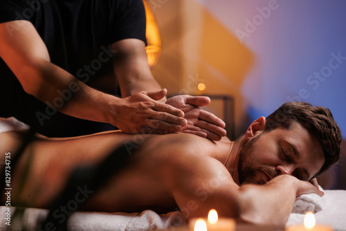 The hands of the male masseur are actively rubbing the visitors back, a therapeutic massage for tired muscles. Point massage in the spa center. Body therapy for a healthy lifestyle.