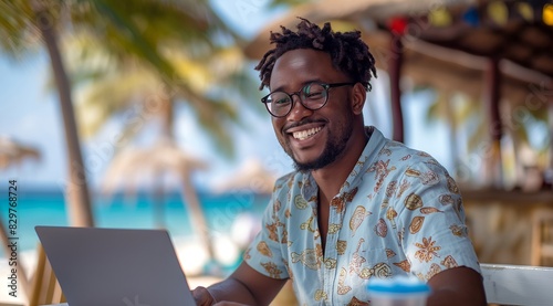 A happy black man in his thirties working on a laptop at a tropical beach bar, using the computer for remote work while vacationing at an exotic island resort with palm trees and blue ocean water.