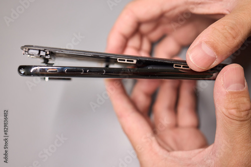 A person halves a broken cell phone, revealing its internal components