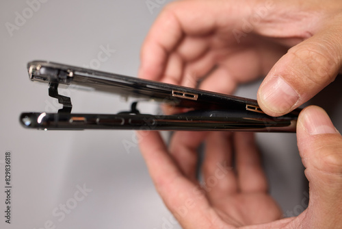 A person halves a broken cell phone, revealing its internal components