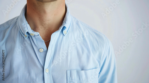 Man wearing rumpled light blue shirt on white background