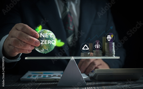 Environmental concept. Businessman holds earth globe with zet zero icon with coin balance and icons for energy and environment, recycling, global risk. Business risk environment Earth day.