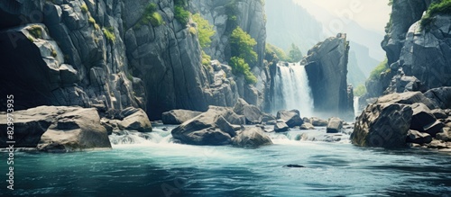 A picturesque waterfall cascades from a rugged cliff gracefully joining a river adorned with scattered rocks Copy space image