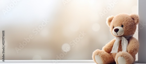 Indoor shot of a cute and lonely teddy bear sitting on a windowsill with ample copy space for text