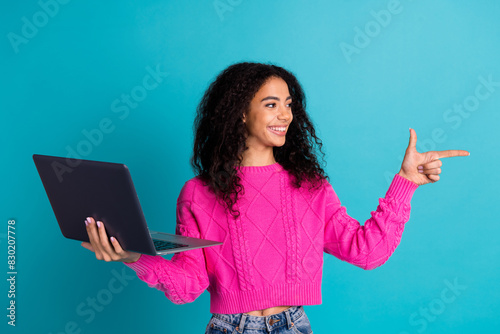 Photo portrait of pretty teen girl hold netbook point look empty space wear trendy pink outfit isolated on aquamarine color background