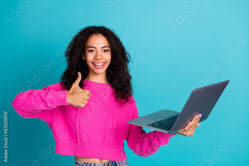 Photo portrait of pretty teen girl hold netbook thumb up wear trendy pink outfit isolated on aquamarine color background