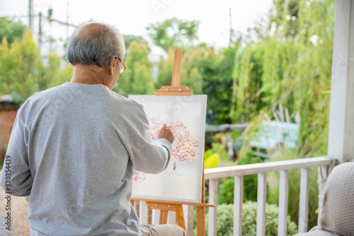 Artist. Asian senior old man painting picture using brush and oil color on canvas, lifestyle elderly people smile paint at his easel, Happy retirement and activity concept