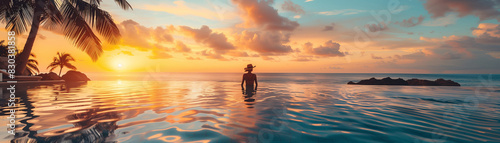A woman is standing in the ocean at sunset. The water is calm and the sky is filled with clouds
