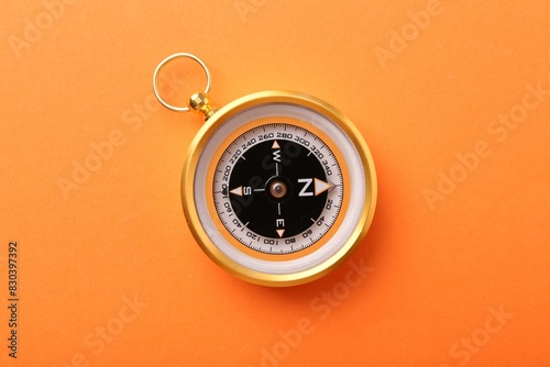 Compass on orange background, top view. Navigation equipment
