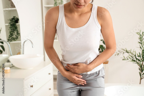 Young woman suffering from menstrual cramps in bathroom, closeup