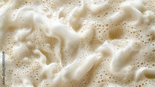  A close-up view of a white foamy surface with a mixture of white and brown liquid and golden flecks at its surface