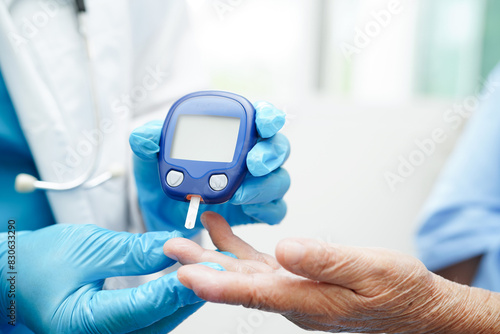 Asian doctor using digital glucose meter for check sample blood sugar level to treatment diabetes.