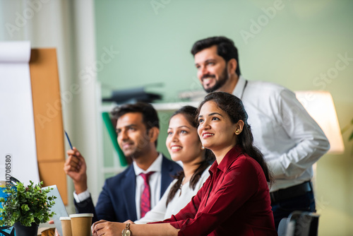 Indian young businesspeople using laptop in group meeting at desk