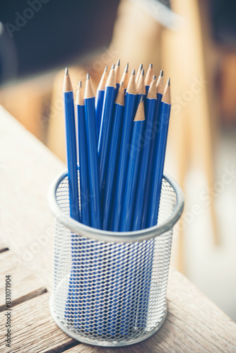 Vertical sharp HB pencil vase office supply decor on wood table. Green decorate home office desk. Wood office desk sharpen blue 2B pencil box home office decorate table