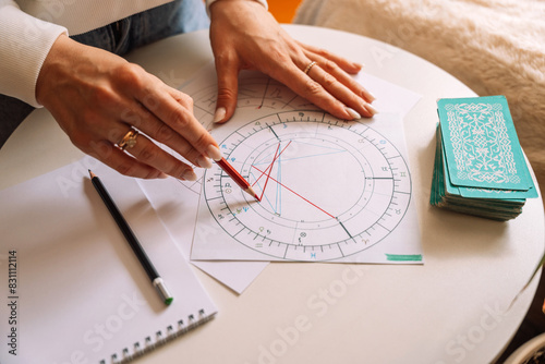 An astrologer draws with a pencil and a ruler on a natal chart.