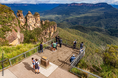 Tourists enjoy the view of the “Three Sisters” rock formation in the Blue Mountains National Park near Katoomba, NSW, Australia