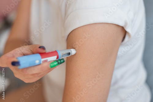 Woman injects herself with the drug Ozempic anti-diabetes pen into her arm at home. Weight loss and decreased blood sugar, concept idea. injector dosing pen for subcutaneous injection