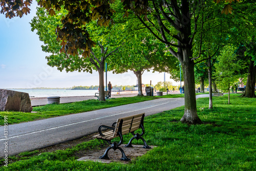 A wooden boardwalk a bike path, and an empty park bench in Toronto's Beaches neighbourhood shot on an evening in May