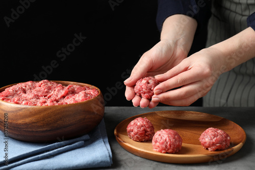 Woman making meatball from ground meat at grey table, closeup