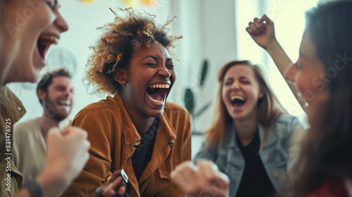 Group of coworkers shares a hearty laugh while gathered in a well-lit office space. Their expressions show joy and camaraderie, highlighting a moment of fun at work
