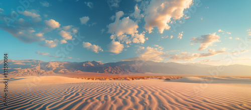 A desert landscape with a blue sky and clouds. The sky is clear and the sun is shining brightly